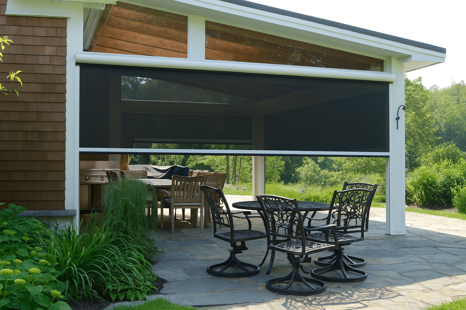 Outdoor roller shades installed on a covered patio, providing shade and privacy for outdoor dining and seating areas.